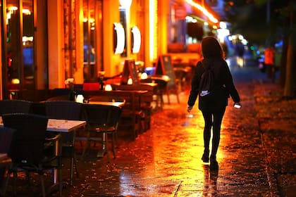 Una mujer camina por una zona de bares con mesas vacías antes del toque de queda nocturno, por la pandemia de coronavirus, en Berlín, Alemania