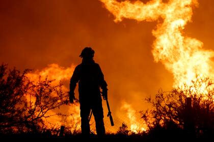 La silueta de un bombero contrasta con las llamas de un incendio forestal, a las afueras de Villa Carlos Paz