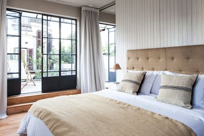 La suite principal con salida a la terraza y vista a la cúpula se hizo en un volumen separado que se reconstruyó por completo. Respaldo de arpillera capitoné contra la pared de machimbre.