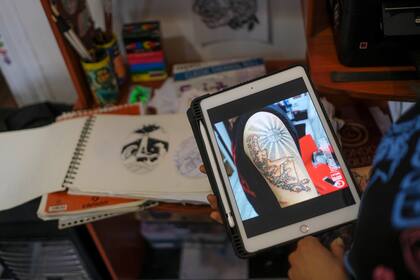 La tatuadora chilena Yumbel Gongora muestra una foto de uno de los tatuajes que hizo en el brazo del presidente electo de Chile, Gabriel Boric, en su estudio de tatuajes en Santiago, Chile, el miércoles 22 de diciembre de 2021. (Foto AP/Matías Delacroix)
