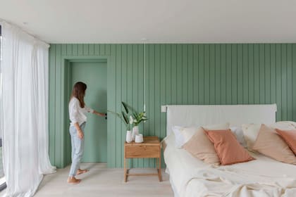 La única pared de color tiene el tono 'Manzanar', de Alba. Mesas de luz (Talleres Sustentables) con artefactos de iluminación (Huup). Almohadones y ropa de cama (La Vie).