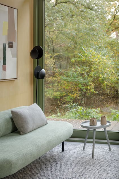 La ventana de piso a techo enmarca el bosque y convierte el living en una extensión del entorno natural.