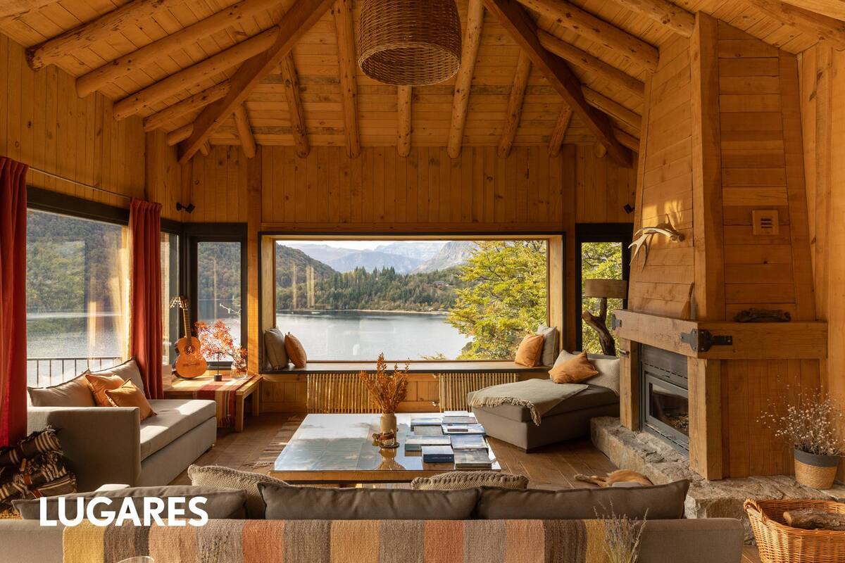 Un rincón del cálido lodge de madera junto al fuego y con vista al lago.