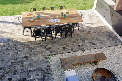 La zona de la parrilla con la mesa de petiribí (Tienda de Hierros) está dispuesta al lado del comedor y de frente a la cocina. En el medio, se generó un patio de piedra partida con bancos de lapacho (Fernando Moy) y un fogón (Tienda de Hierros).