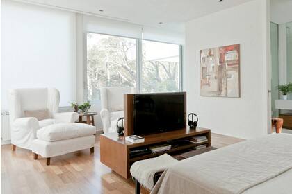 La zona de lectura de este dormitorio está equipada con grandes sillones con apoyapiés revestidos en bull blanco; los mismos asientos se pueden llevar al living a la hora de una reunión