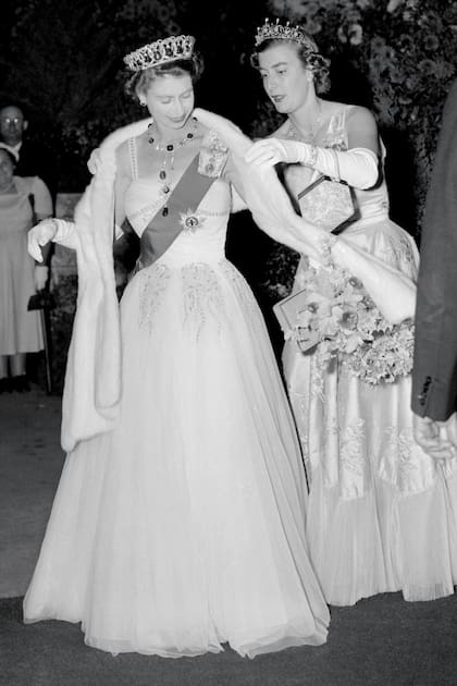 Lady Pamela Mountbatten ajusta la estola de Isabel II en el Royal Ball de Melbourne, en 1954. La Reina y el duque de Edimburgo visitaban la ciudad como parte de su gira por Australia.