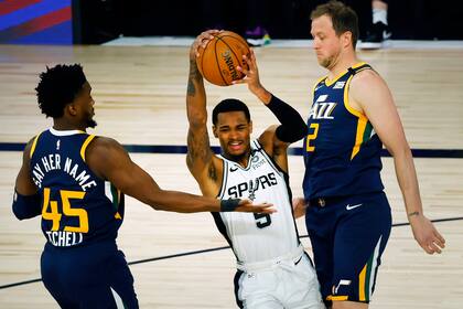 LAKE BUENA VISTA, FLORIDA - AUGUST 13: Dejounte Murray #5 of the San Antonio Spurs drives into Joe Ingles #2 of the Utah Jazz as Donovan Mitchell #45 of the Utah Jazz looks on during the first quarter at The Field House at ESPN Wide World Of Sports Complex on August 13, 2020 in Lake Buena Vista, Flo