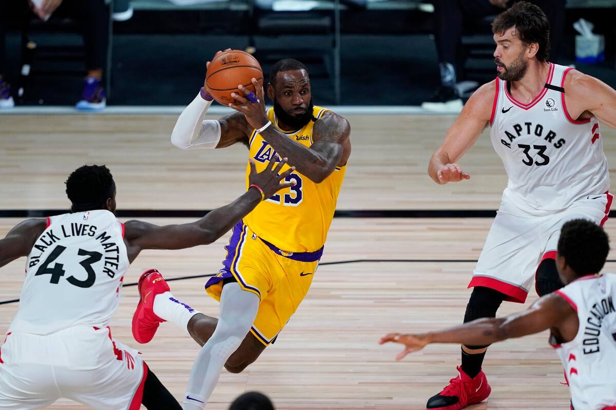 Lake Buena Vista, USA; Los Angeles Lakers forward LeBron James (23) drives to the basket against Toronto Raptors forward Pascal Siakam (43) and center Marc Gasol (33) during the first half.