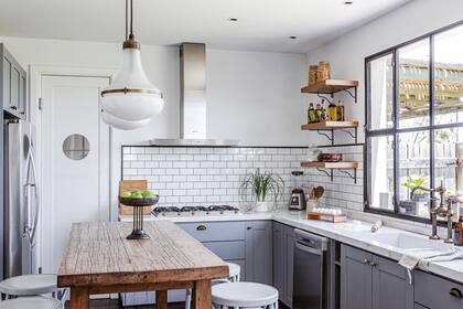 Lámparas colgantes (Mono Giraud). Extractor y anafe (Smeg). Banquetas y frutera heredadas. Barra de petiribí (@cousy_home). Mesada con bacha integrada de Corian. Grifería (Robinet). Huevera de madera (Facundo Monge Muebles).