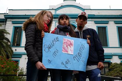 Lara, la hija de Ávalos (centro), junto a su prima y a su novio, frente al Muñiz, ayer