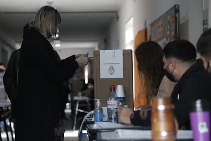 Una votante ingresa el sobre en la urna en una escuela de La Matanza