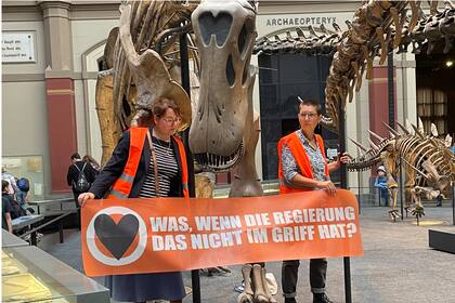 Las activistas que se pegaron a un esqueleto de dinosaurio en el Museo de Historia Natural de Berlín, el 30 de octubre de 2022. (Paul Zinken/dpa via AP)