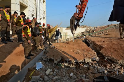 Las autoridades utilizan maquinaria pesada para limpiar los escombros y buscar cadáveres en el lugar del atentado suicida del lunes, en Peshawar, Pakistán, martes 31 de enero de 2023.