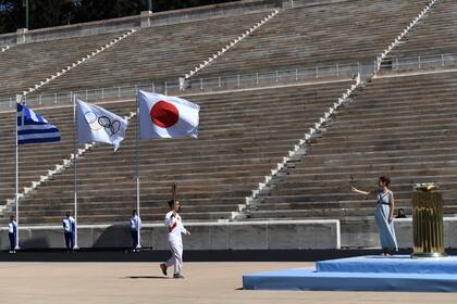 Las banderas de Grecia, de Japón y la olímpica flamean durante la ceremonia de entrega de la llama olímpica