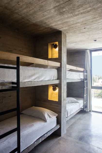 Las camas de obra tienen escalera y barandas de madera (ambos, De Otro Tiempo) y nichos individuales con enchufe y lámparas (Iluminación Castelar).