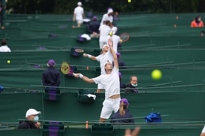 Las canchas de tenis en Roehampton, Londres, un sitio especial donde se juega la qualy de Wimbledon; en primer plano, lanzando la pelota antes de sacar, el argentino Juan Pablo Ficovich.