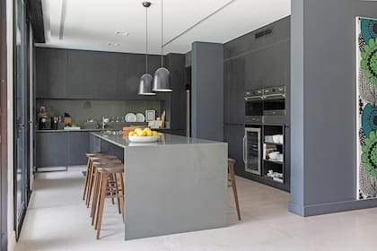 Las columnas existentes generaron un marco para el mueble de la cocina, en melamina ‘Fresno negro’ (Egger). Allí, horno eléctrico, microondas de Smeg y cava para 20 botellas (Winefroz).