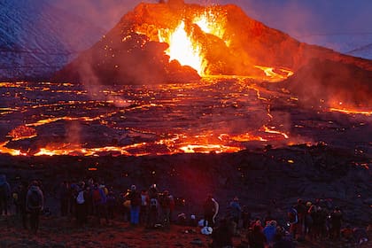 Las figuras de las personas están iluminadas por el resplandor de la lava