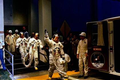 Los astronautas Neil Armstrong, Michael Collins, Buzz Aldrin se dirigen a un vehículo que los llevará a la plataforma de lanzamiento