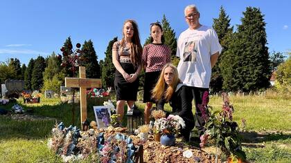 Las hermanas mayores de Vlad, Mia y Masha, con sus padres, Anna y Graham, junto a su tumba en Southampton.