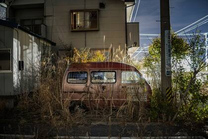 Las hierbas rodean una microvan abandonada en Futuba, la ciudad más cercana al lugar de la fusión nuclear en la prefectura japonesa de Fukushima, 7 de marzo de 2021