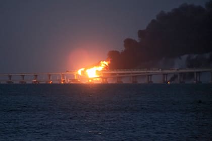 Las llamas y el humo se elevan desde el puente de Crimea que conecta la parte continental de Rusia y la península sobre el estrecho de Kerch, la madrugada del sábado 8 de octubre de 2022. (AP)