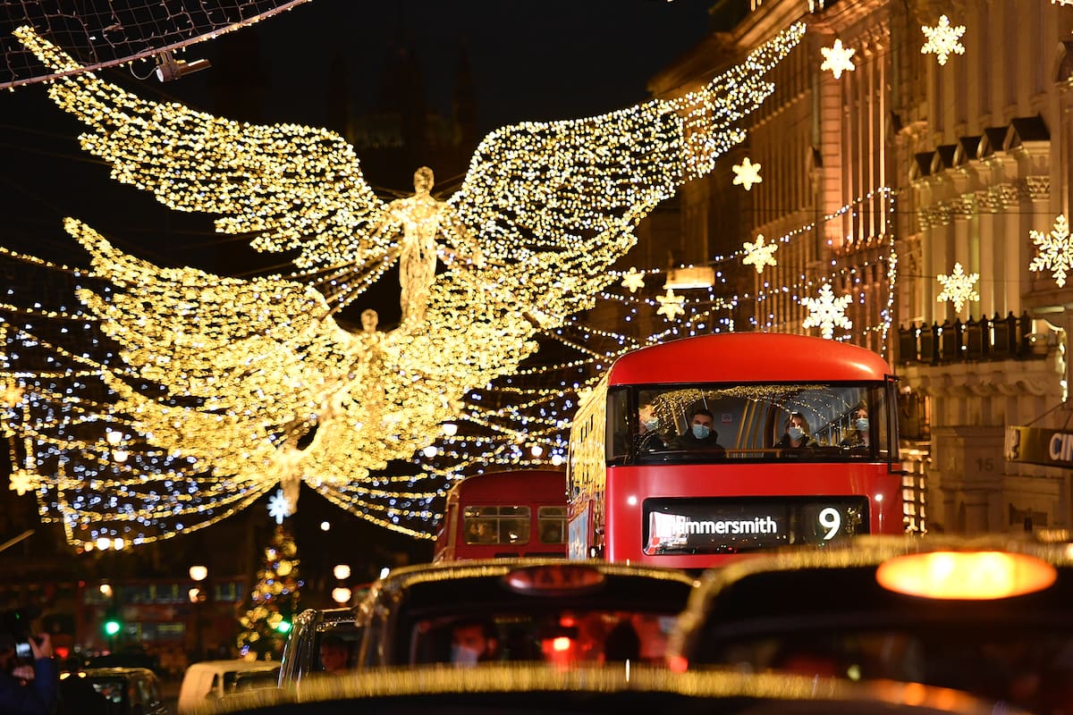 Las luces navideñas brillan mientras los pasajeros viajan en un autobús a lo largo de Piccadilly, Londres, el 12 de diciembre de 2020, ya que con menos de dos semanas para Navidad, la gente aprovecha la flexibilización de las restricciones de Inglaterra sobre la apertura de tiendas