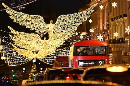 Las luces navideñas brillan mientras los pasajeros viajan en un autobús a lo largo de Piccadilly, Londres, el 12 de diciembre de 2020, ya que con menos de dos semanas para Navidad, la gente aprovecha la flexibilización de las restricciones de Inglaterra sobre la apertura de tiendas