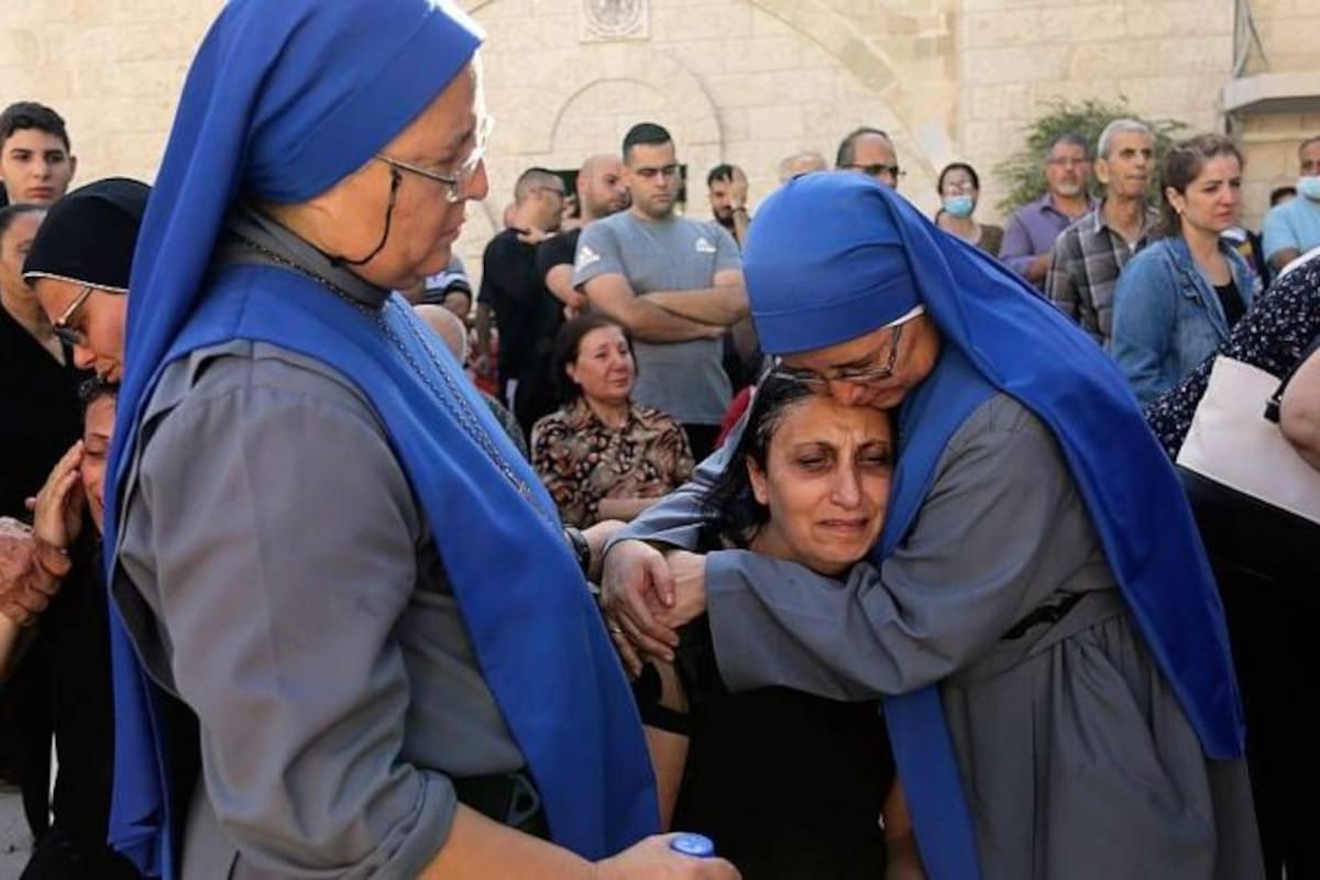 Las mellizas María del Perpetuo Socorro (izq) y María del Pilar Llerena Vargas consuelan familiares de víctimas del bombardeo israelí que impactó en la estructura de la iglesia ortodoxa San Porfirio el 19 de octubre