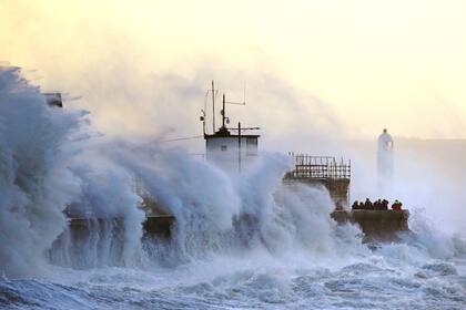 Las olas chocan contra el malecón y el faro de Porthcawl en Porthcawl, Bridgend, Gales, Gran Bretaña