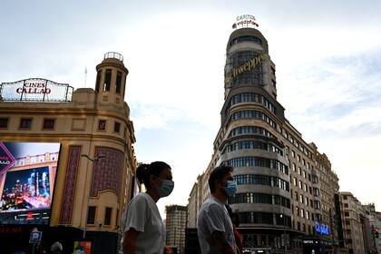 Las personas caminan por la Gran Vía en Madrid el 4 de mayo de 2020 con barbijos, cuando las autoridades comenzaron a flexibilizar un bloqueo nacional para detener la propagación del coronavirus