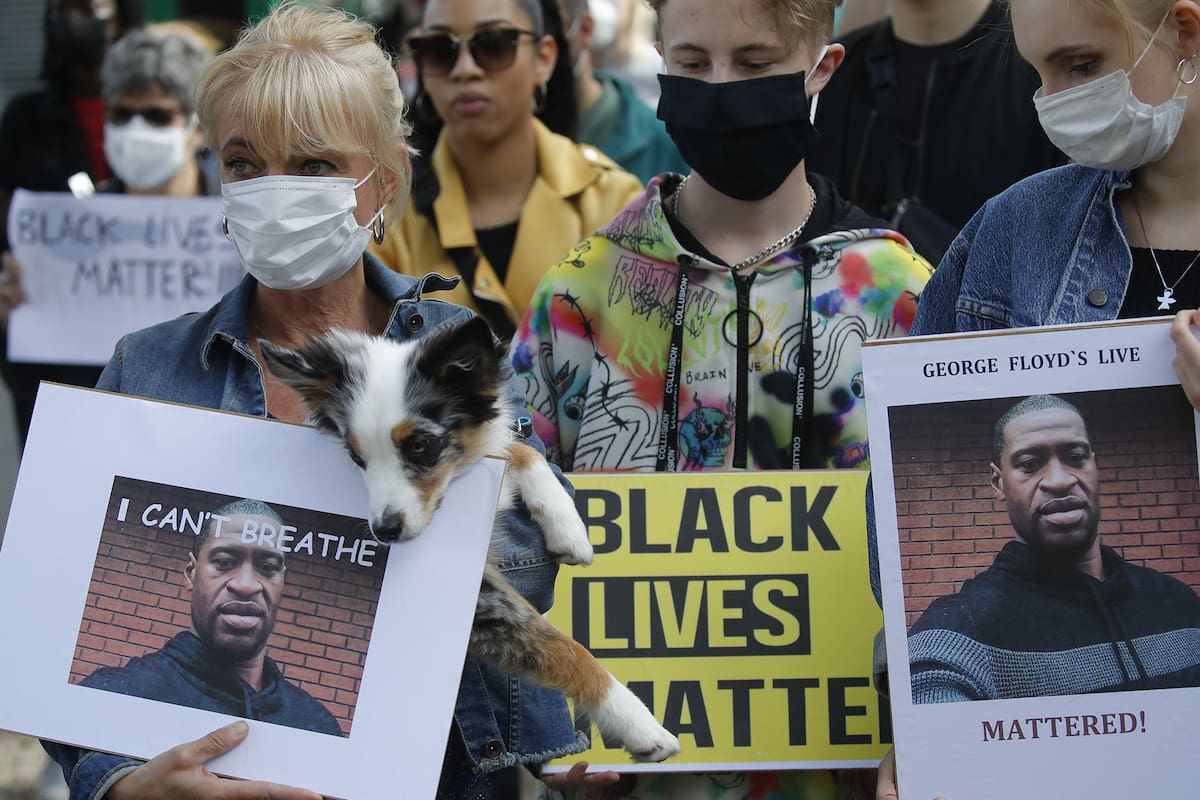 Las personas con máscaras faciales se paran en una protesta y sostienen fotos de George Floyd frente a la Embajada de Estados Unidos en Berlín, el 30 de mayo de 2020