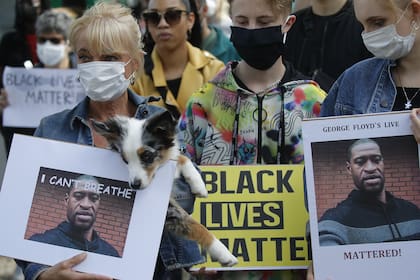 Las personas con máscaras faciales se paran en una protesta y sostienen fotos de George Floyd frente a la Embajada de Estados Unidos en Berlín, el 30 de mayo de 2020