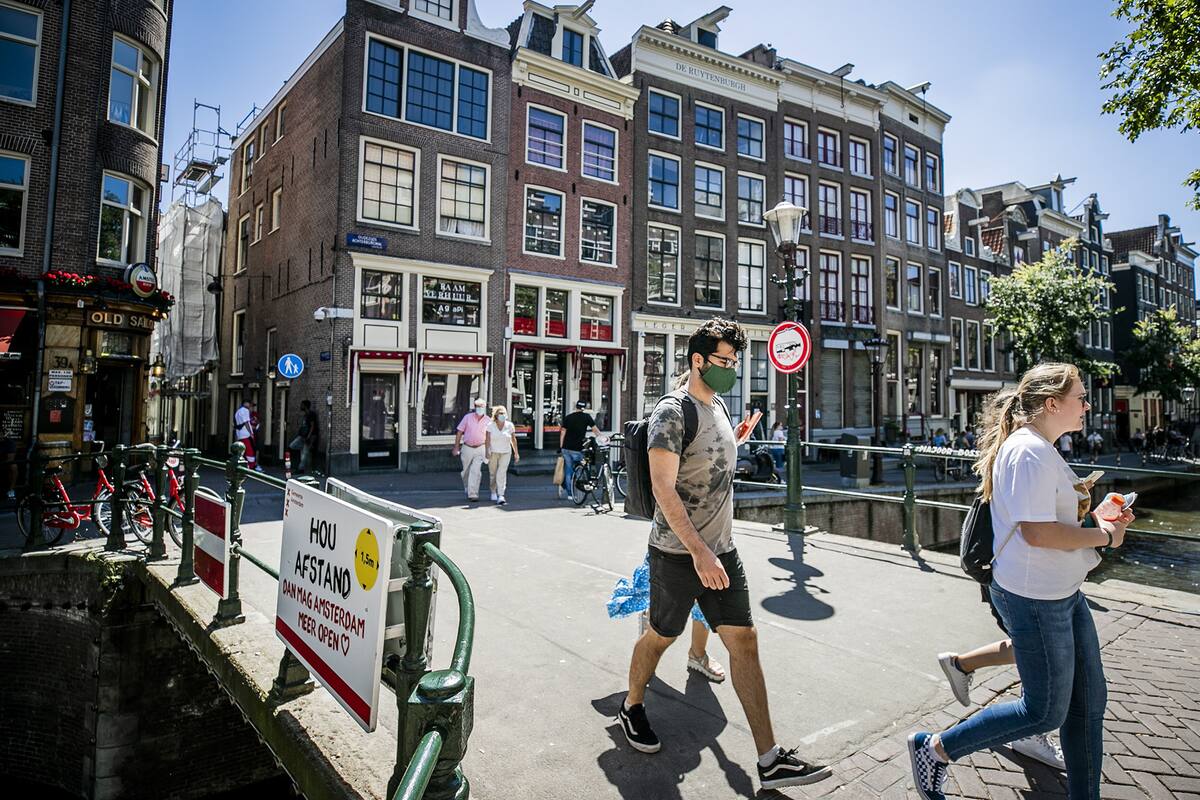 Las personas, con una máscara facial, caminan por un puente del barrio rojo, en Amsterdam, el 5 de agosto de 2020