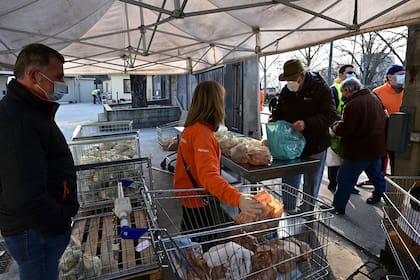 Las personas necesitadas reciben una bolsa con comida gratis en la asociación laica italiana, no partidista y sin fines de lucro llamada "Pane Quotidiano" (Pan de cada día) en Milán, el 8 de marzo de 2021