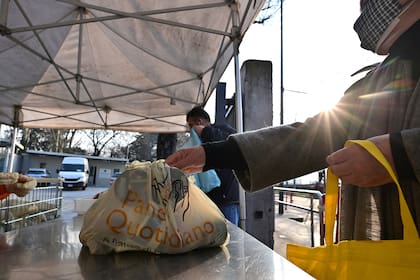 Las personas necesitadas reciben una bolsa con comida gratis en la asociación laica italiana, no partidista y sin fines de lucro llamada "Pane Quotidiano" (Pan de cada día) en Milán, el 8 de marzo de 2021