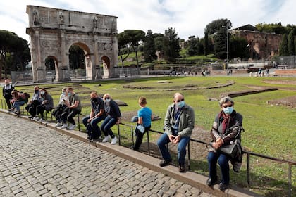 Las personas que usan máscaras faciales se ven junto al Arco de Constantino mientras Italia adopta nuevas restricciones destinadas a frenar el aumento de las infecciones por coronavirus (COVID-19), en Roma.