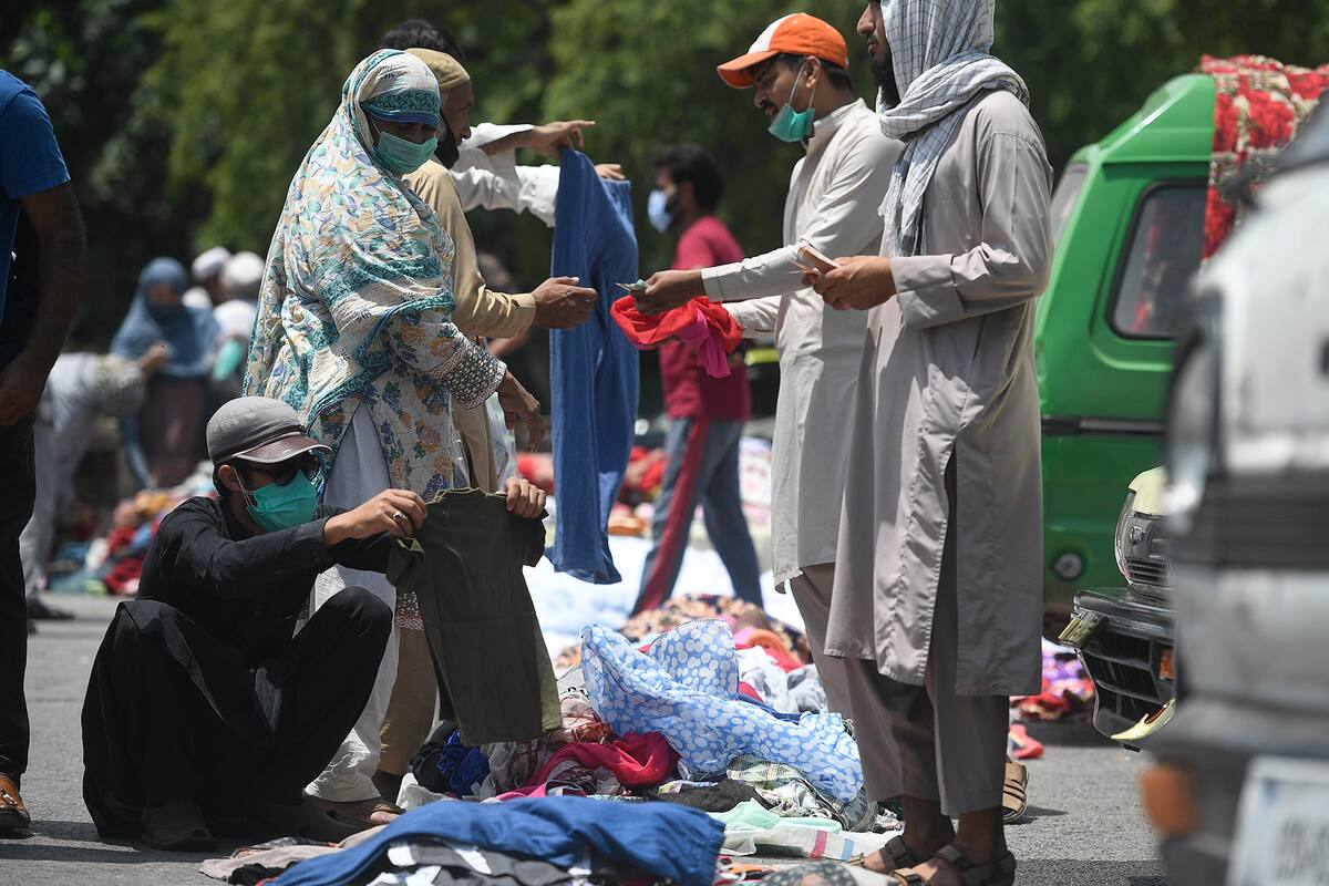 Las personas que usan mascarillas compran ropa en una calle en Islamabad, Paquistán, el 12 de junio de 2020