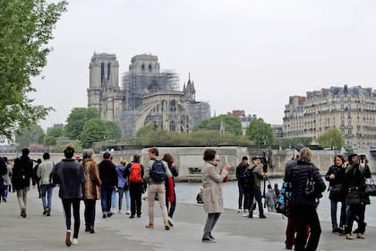 Residentes y turistas sacan fotos a la catedral el día después del voraz incendio
