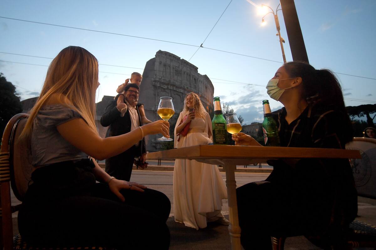 Las personas se reúnen para tomar un aperitivo frente a un bar junto al Coliseo en Roma, el 18 de mayo de 2020