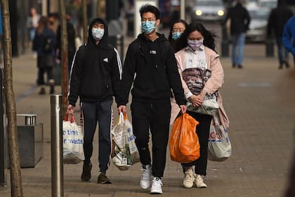 Las personas usan barbijos protectoras en el centro de Leeds en la mañana del 21 de marzo de 2020, un día después de que el gobierno británico dijo que ayudaría a cubrir los salarios de las personas afectadas por el brote de coronavirus, ya que endureció las restricciones para frenar la propagación