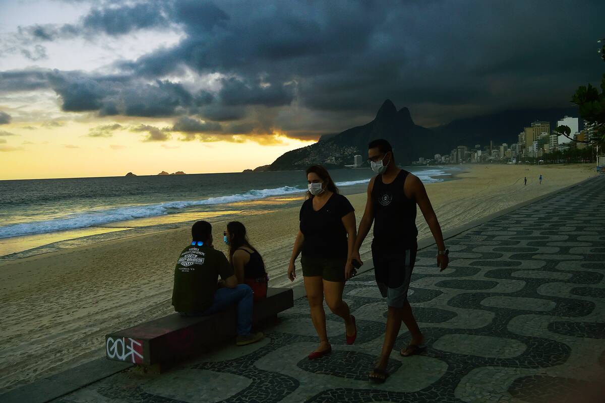 Las personas usan mascarillas como medida preventiva contra el nuevo coronavirus, mientras caminan por la playa de Ipanema en Río de Janeiro el 19 de mayo de 2020