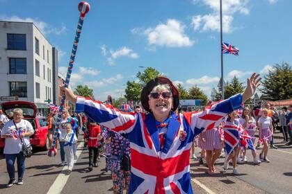 Las personas visten los colores nacionales británicos participan en una fiesta callejera en Shankill, en Belfast, Irlanda del Norte, el 4 de junio de 2022 como parte de las celebraciones del jubileo de platino de la reina Isabel II. (Foto de Paul Faith / AFP)