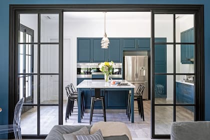 Las puertas corredizas de hierro con vidrio repartido (Del Hierro Design) sectorizan el área del family room contiguo.
