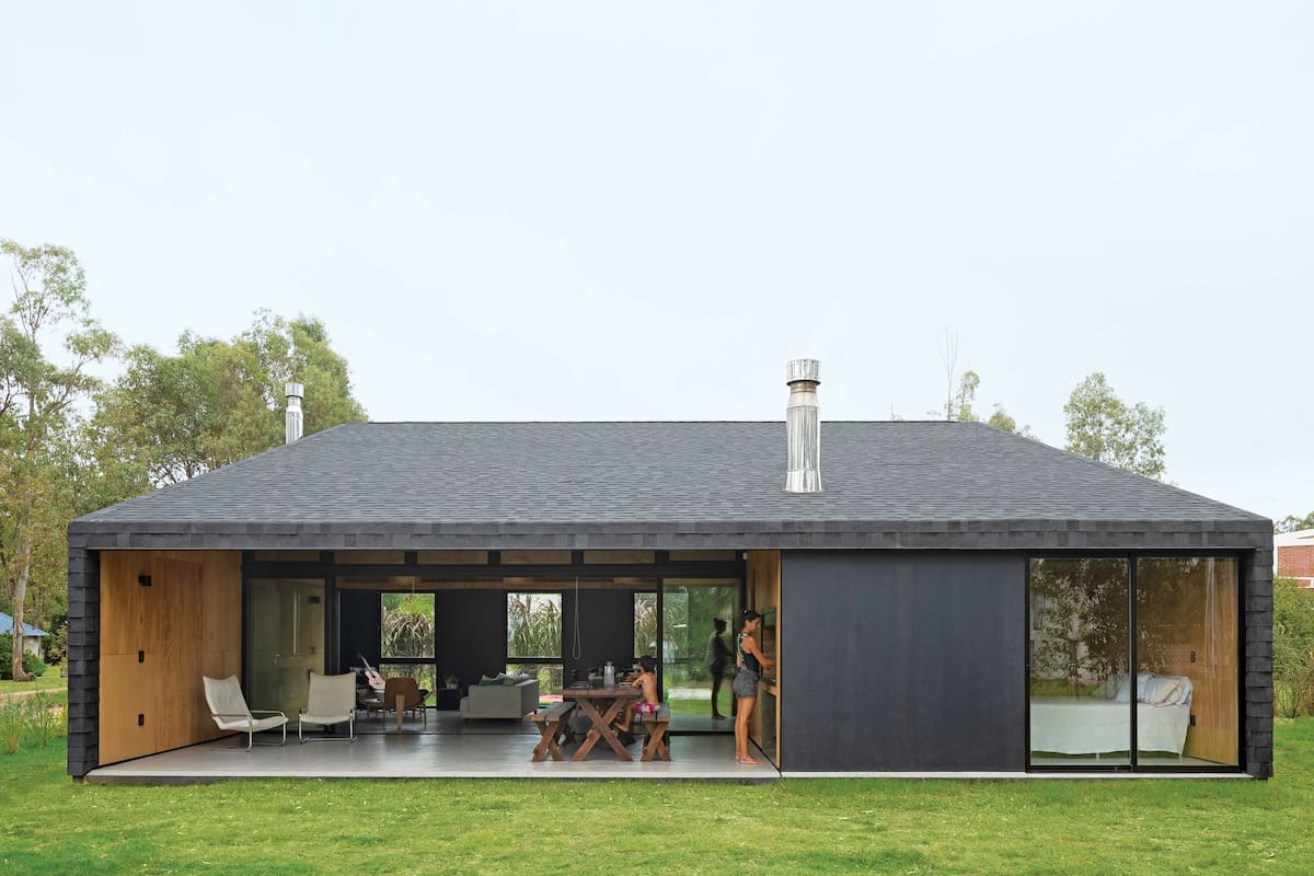 Las tejas asfálticas, frecuentes en techados de construcciones en seco, revisten también el muro para conseguir el efecto de continuidad que caracteriza la obra.