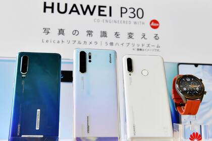 Las tres versiones del teléfono P30 de Huawei junto a un reloj inteligente Huawei Watch