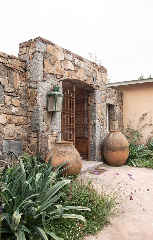 Las vasijas como esculturas se unen a los tonos de la pared de piedra.