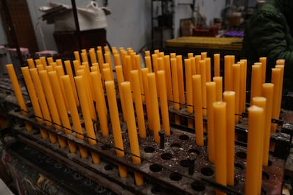 Las velas de cera de abeja avanzan alineadas por una de las máquinas de Lumen Christi, donde parte de la producción se realiza de manera mecanizada