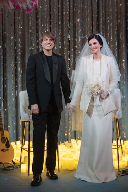 Laura lució un traje de novia color marfil, cuello redondo y mangas al codo, de Armani, que acompañó con un clásico velo, guantes largos de plumetí, collar de perlas y un ramo de flores secas. Por su parte, Paolo apostó por un estilismo más informal en color negro.