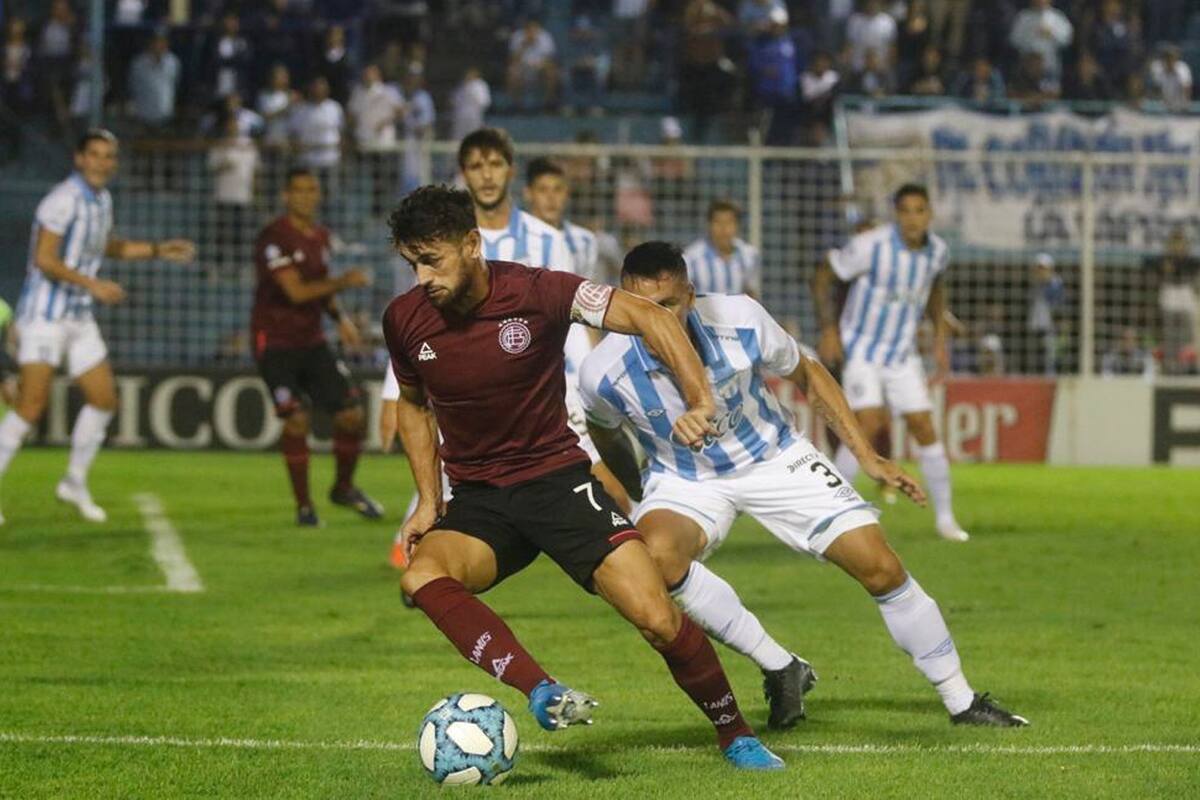 Lautaro Acosta domina la pelota delante de Fabián Monzón.